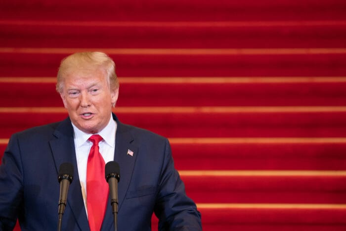 President Trump talking against a red backdrop.
