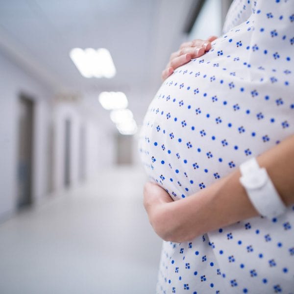 A pregnant woman cradles her belly as Trump cracks down on birth tourism.