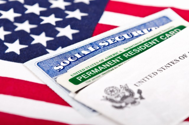 Social security card and green card on an American flag